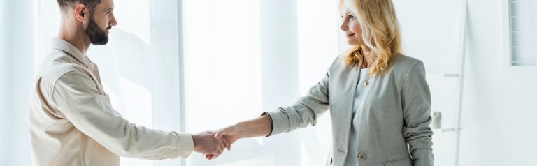Panoramic shot of recruiter and handsome employee shaking hands